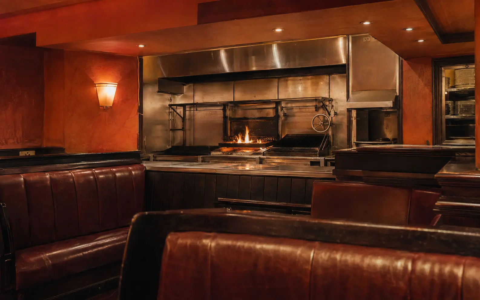 Editorial reconstruction of an early-2000s steakhouse with leather booths and a visible open chargrill