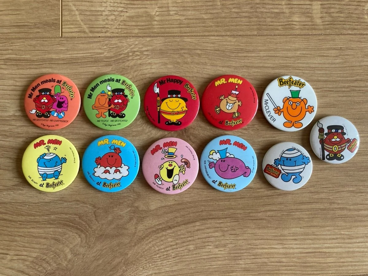Eleven 1980s Mr Men Beefeater badges laid out in a row